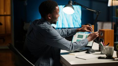 Siyah adam programını bir planlamacıyla düzenliyor ve bir hatırlatma koyuyor, yapışkan bir not yazıyor ve internete takılıyor. Modern üretken adam araştırma için bir not yazar. Kamera B.