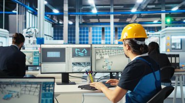 Robot kollarını test etmek için bilgisayar kullanan fotovoltaik fabrikası mühendisi güneş panellerini montaj hatlarına yerleştiriyor. Profesyonel olarak bilgisayar masasında oturup güneş santrali ağır makine ünitelerini, kamera A 'yı inceliyorum.