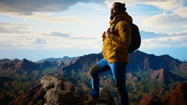 Sıcak giysiler içindeki gezgin panoramik dağ sırasına bakıyor, macera duygusunu kucaklıyor ve en nefes kesici manzaraları keşfetmekle gelen kişisel gelişimi kucaklıyor. Kamera A.
