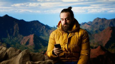 Doğa aşığı dağın tepesinde rahatlıyor telefonuyla manzaraya bakan manzaralı bir bakış açısıyla internete giriyor. Yürüyüşçü her zaman çevrim içi ve bağlı kalıyor, panoramik manzara. Kamera B.