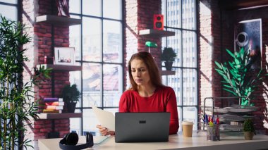 Masasında oturmuş araştırma kağıtlarını okuyan ev bilgisayarında birden fazla iş yapan sıradan bir kadın. Yetişkin dalışı profesyonel ya da kişisel gelişim konuları. Kamera B.