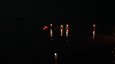 Suda yüzen çiçeklerle dolu loy Krathong festivali. Canlı Tayland festivali sahnesi. Sahilde parlayan mumlarla çiçeklerin sunulduğu yer..