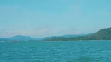 Tekne, ahşap yelkenli teknesiyle el değmemiş tropikal bir adaya doğru gidiyor, sakin mavi sular ve yemyeşil yeşilliklerle çevrili küçük bir adaya yaklaşıyor. Egzotik Tayland manzarası.