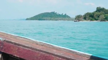 Tayland kıyılarındaki pitoresk bir adanın yakınında yüzen tekne, kıyı boyunca sürüklenen geleneksel ahşap yelkenli, bereketli palmiye ağaçları ile nefes kesici bir tropik manzara ortaya çıkarıyor..