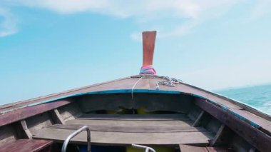 Geleneksel Tayland teknesi turkuvaz dalgalı açık denizde, tropikal sularda yüzen tekne tenha bir adaya doğru hareket ediyor, manzaralı deniz manzarası ve yaz tatilleri sergiliyor..