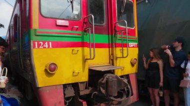 Tayland, Kasım 2024 - İnsanlar Bangkok demiryolu pazarından geçen treni izliyor. Trenin, yerel gıda satan satıcılarla ünlü bir Tayland pazarından geçtiği eşsiz bir kültürel deneyim..