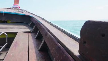 Geleneksel tekne Tayland 'ın küçük bir adasına doğru gidiyor. Tayland tropikal sularındaki ahşap tekne göz kamaştırıcı deniz manzaraları ve parlak bir yaz gökyüzü ile çevrili ıssız bir adaya doğru ilerliyor..