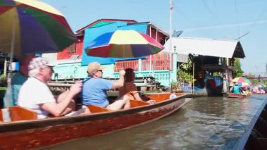 Tayland, Kasım 2024 - Yüzen pazar satıcıları için teknelerde yüzen turistler, kanaldaki yelkenlilerinden geleneksel Tayland yemekleri veya hediyelik eşyalar alıyorlar. Suda ünlü bir pazar yeri..