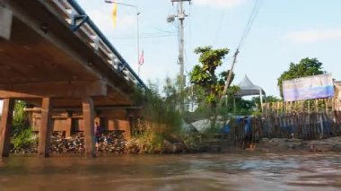 Tayland, Kasım 2024 - Tropikal bir Tayland köyünde tekne gezisi, yeşil ve geleneksel evlerle çevrili huzurlu nehir kanallarında süzülen bir yelkenliyle manzaralı bir macera.