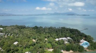 Tayland adasında kumlu sahilleri ve dalgaları olan, mavi gökyüzü olan sakin deniz kıyısından kaçan lüks tatil beldelerinin insansız hava aracı görüntüleri. Güzel Tayland kıyıları Tropik bir cennet gibi doğal güzellikler.