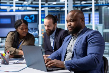 Üretim fabrikası yöneticileri, dizüstü bilgisayardaki operasyonel verileri gözden geçirmek için hissedarlarla buluşuyor. Yatırımcılar not defterindeki ölçülere bakıyorlar, ticari genişleme için potansiyel yatırım stratejilerini araştırıyorlar