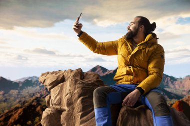 Yürüyüşçü maceracı dağın tepesindeki nefes kesici manzarayı yakalar, uzak bir dağ sırasına bakar ve vahşi doğanın güzelliğini kucaklar. Mucizeleri keşfetmenin sevinci.