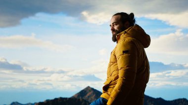 Kararlı gezgin, gökyüzünün enginliği ve engebeli zirvelerden esinlenerek destansı dağ sırasına ve manzaraya bakıyor. Açık havayı kucaklamanın mükafatı. Kamera B.