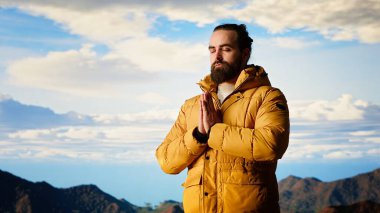 Keyifli bir doğa aşığı dağ sırasının tepesinde meditasyon yapıyor, meditasyon yapıyor ve rahatlık ve zihinsel berraklık için derin nefesler alıyor. Huzurlu zen yürüyüşçüsü tırmanmayı sever. Kamera B.