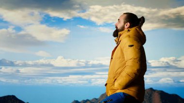 Yürüyüşçü dağların panoramik manzarasına hayran olmak için bir dakikasını ayırır, uzaklığa ve manzaraya bakar. Temiz hava, manzaralı arka plan ve bir kaşif için huzurlu bir ortam. Kamera B.