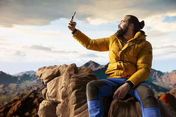 Yürüyüşçü maceracı dağın tepesindeki nefes kesici manzarayı yakalar, uzak bir dağ sırasına bakar ve vahşi doğanın güzelliğini kucaklar. Mucizeleri keşfetmenin sevinci.