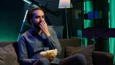 Kanepede oturup abonelik üzerine yayın yapan ve patlamış mısırın tadını çıkaran komedi dizisi için TV kullanan eğlenceli bir insan. Televizyondaki komik şovlara gülen, abur cubur yiyen, kamera A.