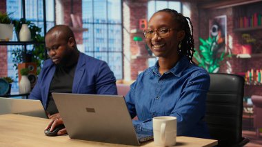 Afrika kökenli Amerikalı bir kadın partneriyle görevleri çözmek için not defterinde raporları kontrol ediyor, evlerinin rahatlığından bağımsız işler yapıyor. Bilgisayarla araştırma yapan odaklanmış insanlar. Kamera A.