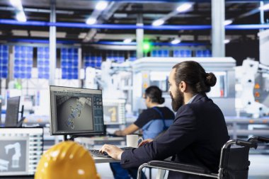 Fotovoltaik fabrikasında engelli biri bilgisayar üzerinde çalışıyor, sistem arızası teşhisi koyuyor. Güneş panelleri, tekerlekli sandalyedeki belden aşağısı felçli çalışanı sistem güvenilirliğini koruyor.