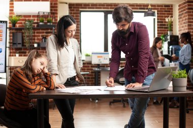 Beyaz kadın sakallı adamla mali evrakları incelerken kızı masada sıkılmış bir şekilde oturuyor. Erkek meslektaş, yeni kurulan bir şirkette genç anneyle muhasebe bilgilerinde bir hataya işaret ediyor.