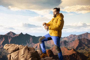 Dağ sıralarında gezen maceraperest susuzluk için durur manzaraya ve vahşi doğaya hayran kalır. Genç kaşif su içiyor ve su şişesini su içmek için kullanıyor..