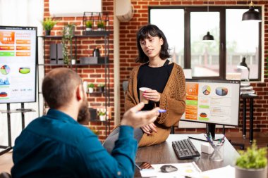 Çalışanlar yeni başlayan şirketler için pazarlama stratejisini açıklarken, kadın yönetici masada oturuyor ve elinde kahve fincanı tutuyordu. Genç adamı dinleyen iş kadını tuğla duvar ofisindeki finansal analizi anlattı.