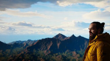 Heyecanlı gezgin, dağın zirvesine tırmandıktan sonra kollarını kaldırıp doğanın panoramik güzelliğinin tadını çıkarıyor. Uçsuz bucaksız gökyüzüne ve uçsuz bucaksız manzaraya hayranlık duyuyorum. Kamera A.