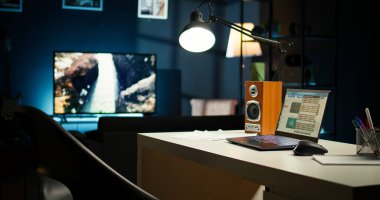 Çağdaş bir ofis düzeneği olan rahat bir apartman dairesi. Ahşap mobilyalar, televizyon ve ev bitkileri modern iç tasarımı, konfor ve yaratıcılığı ön plana çıkarıyor..