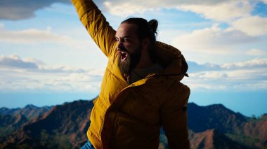 Tırmanışçılar nefes kesen bir dağ zirvesinde manzaranın keyfini çıkararak, başarılı bir yolculuktan sonra kendini mutlu ve mutlu hissederek kutluyorlar. Gururlu yürüyüşçü azmi somutlaştırır. Kamera A.
