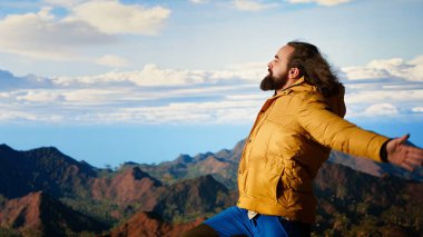 Macera Avcısı, başarılı bir tırmanışın hazzıyla zirvede durur. Gurur duyar ve dağın tepesindeki sert rüzgarın tadını çıkarır. Özgürlüğü ve doğayı sevmek. Kamera B.