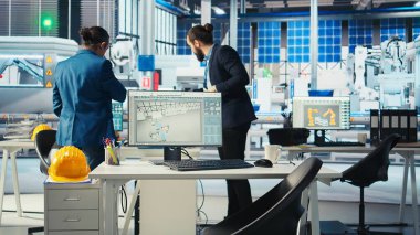 Fotovoltaik fabrikası yöneticisi güneş mühendisliği ekibiyle yeni sistem tasarımı ve güvenilirliğini geliştirmek için çalışıyor. Güneş paneli üretim tesisi müfettişi çalışanlara geri bildirim sağlıyor