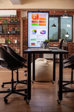 Dijital sunumlar için sandalyeler ve monitörlerle organize edilmiş modern çalışma ortamında kimse yok. Şirket toplantıları için kullanılan boş başlangıç ofisi, analitik özet gösteren öncü ekran paneli ile ayarlandı.