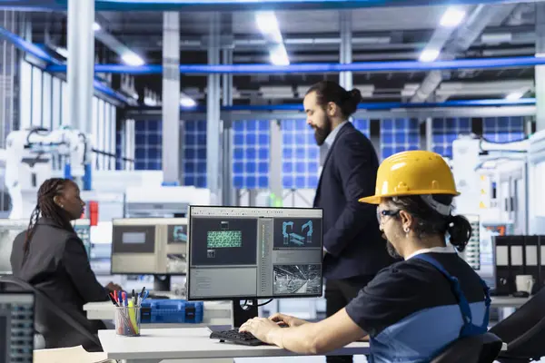 Güneş paneli fabrikasındaki endüstriyel otomasyon teknisyeni bilgisayar yazılımıyla robot makine ayarlarını ayarlıyor. Fotovoltaik fabrikası çalışanı dişli performans sorunları teşhis ediyor