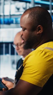 Dikey video endüstrisi 4.0 endüstriyel fabrika mühendisliği ekibi tablet üzerinde CAD uygulaması kullanarak yeni robotik makineler tasarlıyor. Takım çalışması akıllı fabrika çalışanları otomasyon ekipmanları, kamera programlıyorlar.