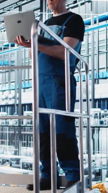 Dikey video endüstrisi 4.0 endüstriyel fabrika uzmanı robot imalat makinelerini cihaz kullanarak otomatize ediyor. Akıllı fabrikada dizüstü bilgisayar kullanarak yapay zeka uygulayan yaşlı bir çalışan.