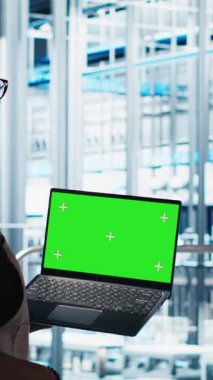 Dikey video akıllı fabrika teknisyeni robot kolları kontrol ediyor. Model defter kullanarak, kapat. Sektör 4.0 endüstriyel santraldeki mühendis otomatik makineleri yeşil ekran dizüstü bilgisayar ve kamera A kullanarak kontrol ediyor.