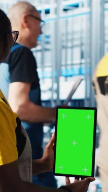 Dikey video akıllı fabrika uzmanı izole ekran tableti kullanarak robotik kolları yönetiyor, kapat. Endüstri 4.0 endüstriyel fabrika çalışanı otomatik makineleri krom anahtar cihazı ve kamera kullanarak kontrol ediyor.