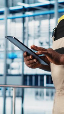 Dikey video akıllı fabrika uzmanı otomatik sistemleri test etmek ve güvenilirliği sağlamak için dijital cihaz uygulaması kullanıyor. İşçi, algılayıcı verilerine dayanarak darboğazları belirlemek ve ekipmanları optimize etmek için tablet kullanır