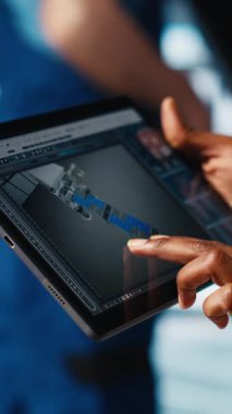 Dikey video endüstrisi 4.0 endüstriyel fabrika mühendisi tablet üzerinde CAD yazılımı kullanarak yeni robotik makineler tasarlıyor. Otomasyon için dijital aygıt uygulaması kullanan akıllı bir fabrika teknisyeni