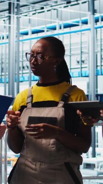 Dikey video akıllı fabrika ekip lideri tesis katındaki robot silah operasyonunu denetleyen çalışanlarla konuşuyor. Endüstri 4.0 fabrika işçileri, sorunlu çatışma hatalarıyla ilgili beyin fırtınası yapıyorlar