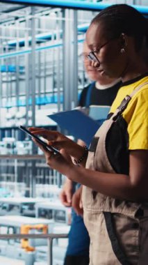 Akıllı fabrikadaki dikey video mühendisi otomatik iş akışlarını ve kontrol sistemlerini uyguluyor manüel işlemleri bilgisayarlı süreçlerle değiştiriyor. Teknisyen sensörleri üretime entegre ediyor