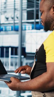 Dikey video endüstrisi 4.0 endüstriyel fabrika uzmanı dizüstü bilgisayarda CAD yazılımı kullanarak yeni robotik makineler tasarlıyor. Otomasyon ekipmanları için not defteri kullanan akıllı bir fabrika teknisyeni.