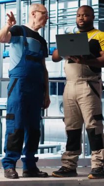 Verileri toplayıp analiz etmek için akıllı fabrikada stajyer doktorla konuşan dikey video mühendisi. Tecrübeli teknisyen stajyerin endüstriyel santralde izleme yazılımı kullanmasına yardım ediyor.