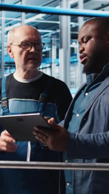 Akıllı fabrikayı denetleyen dikey video yöneticisi otomatik sistemleri test eden mühendislere talimatlar veriyor. Endüstri 4.0 endüstriyel fabrika denetleyicisi çalışanları darboğazları tespit etmekle görevlendirdi