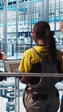 Dikey video mühendisleri, sistem performansına bakarak akıllı fotovoltaik fabrikasını denetleyen müdürle konuşuyor. İşçiler güneş panellerinden geri bildirim alıyorlar. Fabrika denetleyicisi, enerjiyi takip ediyor.