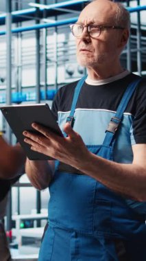 Dikey video sanayi fabrikası kıdemli mühendisi sektör 4.0 otomatik iş akışı ve kontrol sistemlerini uygulayarak işlemleri bilgisayara geçirir. Yaşlı uzman sensörleri üretime ve kameraya entegre ediyor