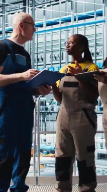 Dikey video akıllı fabrika mühendisliği ekibi tesis katındaki robotik silah operasyonunu denetliyor. Endüstri 4.0 fabrika takım arkadaşı sistem performansını ve sorununu izliyor