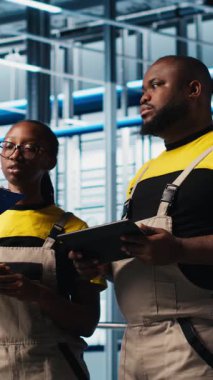 Dikey video Photovoltaics akıllı fabrika ekip lideri ve verileri analiz eden işçiler. Sanayi kıdemli mühendisi ve iş arkadaşları 4.0 güneş panelleri yenilenebilir enerji değerlendirme ölçümleri üreten tesis