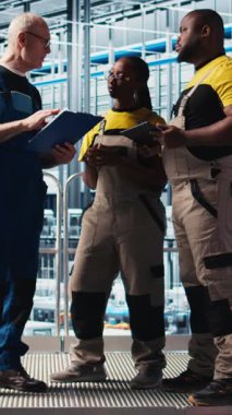 Dikey video Photovoltaics akıllı fabrika ekip lideri ve verileri analiz eden işçiler. Sanayi kıdemli mühendisi ve iş arkadaşları 4.0 güneş panelleri yenilenebilir enerji değerlendirme ölçümleri üreten tesis
