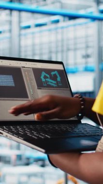 Dikey video güneş panelleri fabrika işçisi IoT sensörleri aracılığıyla enerji üretimini takip ediyor. Akıllı fotovoltaik fabrikasındaki mühendis dizüstü bilgisayar ve kamera A 'daki sistem performans ölçümlerine bakıyor.